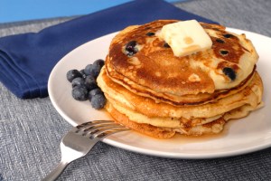 A stack of blueberry pancakes with maple syrup